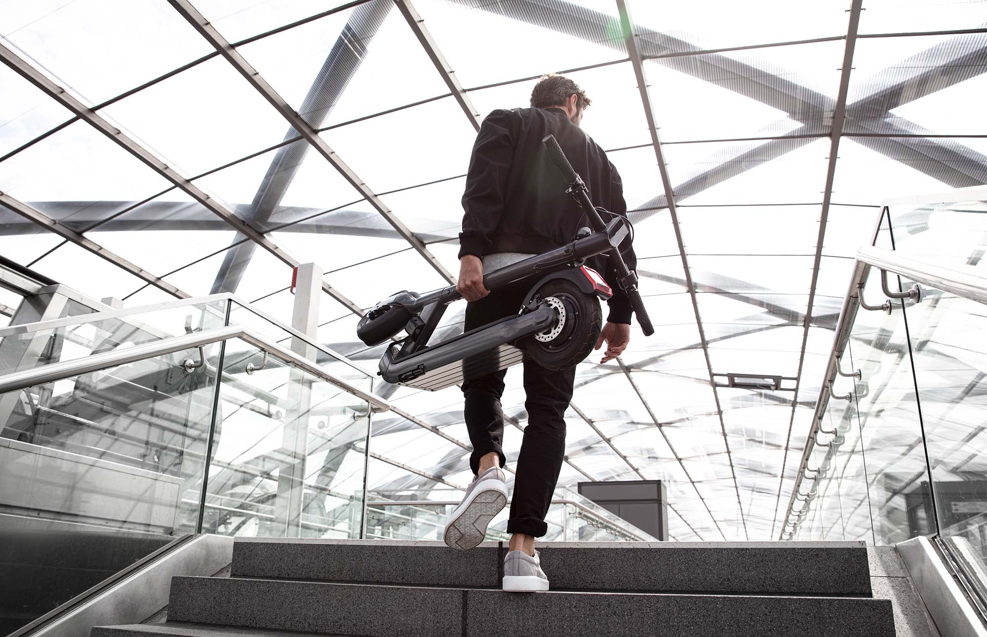 eScooter Egret Pro wird von Mann die Treppe herauf getragen