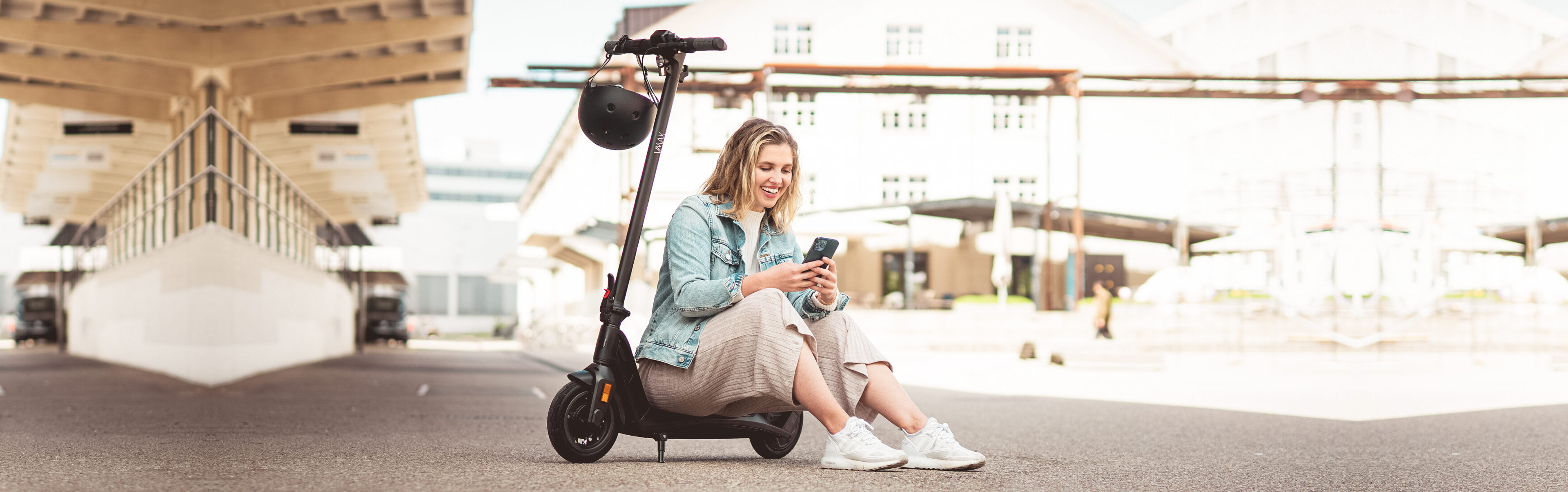 eScooter VMAX mit sitzender jungen Frau und Handy
