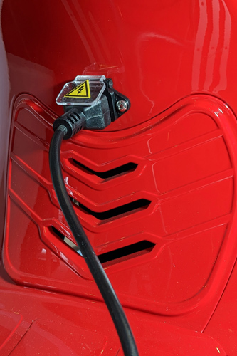 Steckerbuchse zum Außenaufladen eines Retro Elektrorollers E.F.O EV 4000 in rot mit angestecktem Ladekabel