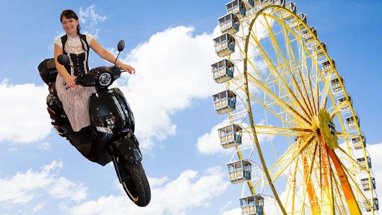 Frau auf Elektroroller im BAyerischen Himmel mit Riesenrad